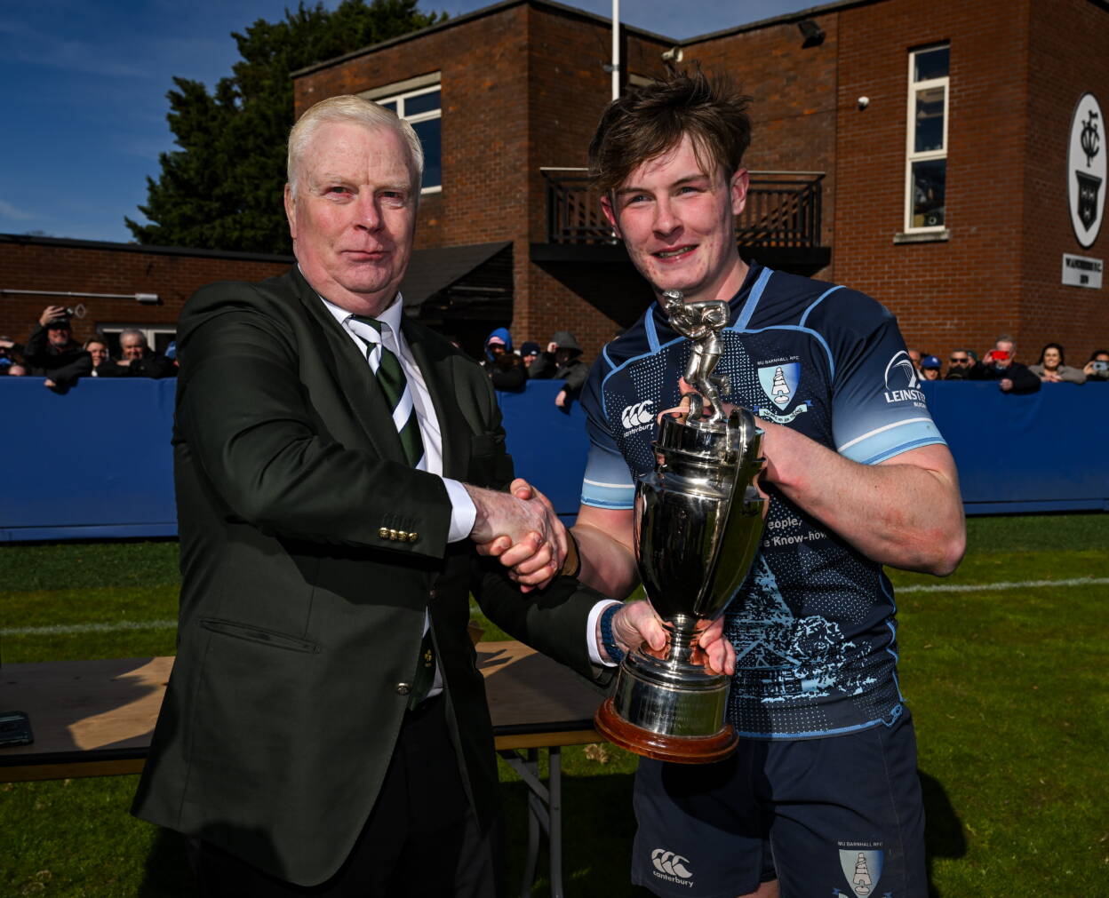 IRFU Committee member Joe McDermott presents the cup to MU Barnhall captain Alex Crowley